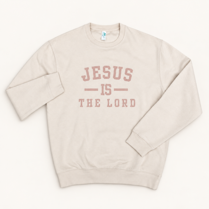 Beżowa bluza bez kaptura z okrągłym dekoltem i różowym napisem „Jesus is the Lord” na jasnym tle.